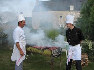 two men in chef hats cooking on a grill at La Ferme des 3 Maillets in Avaray