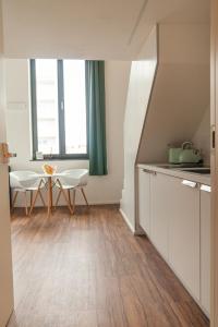 una cocina con armarios blancos y una mesa con sillas. en Soulfactory Apartments, en Neu-Ulm