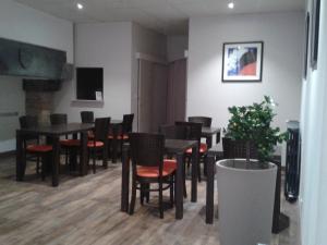 uma sala de jantar com mesas pretas e cadeiras vermelhas em Le Minotel em Vitré