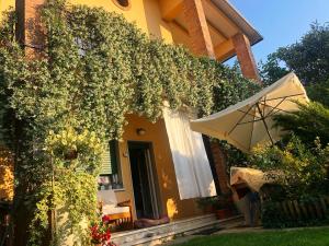 a yellow house with an umbrella and a patio at casa Gian in Lazise