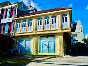 a yellow building with white windows on a street at Orm Thong Hotel - SHA Plus in Kathu