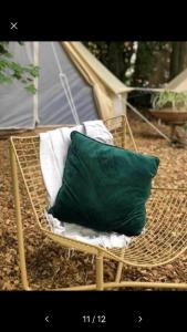 a green pillow sitting on a rattan chair at Into the Green Glamping- Maple in Markt Nordheim