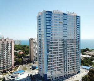 ein hohes blaues Gebäude mit dem Ozean im Hintergrund in der Unterkunft New Coast Apartaments Odessa near sea in Odessa