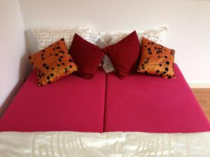 a pink bed with four pillows on it at Bed & Breakfast Maria in Rotterdam
