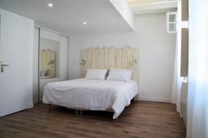 a bedroom with a white bed with a wooden headboard at Maison d'hôtes City Break MIRADOUR in Bayonne