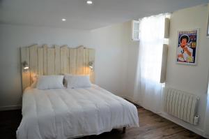 a bedroom with a white bed with a wooden headboard at Maison d'hôtes City Break MIRADOUR in Bayonne +60 photos