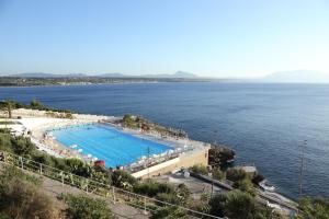 a large swimming pool next to a large body of water at Perla Del Golfo Resort in Terrasini