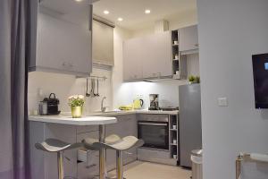 a kitchen with white cabinets and a table and stools at Check Point - Acropolis in Athens