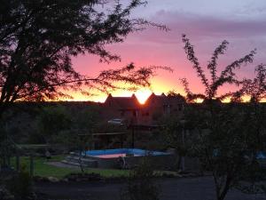 a sunset over a pool in a yard with a house at Teri-Lemveli Lodge in Beaufort West