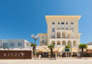 a large white building with palm trees in front of it at BO Hotel Palazzo in Poreč