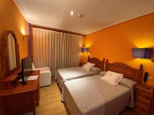 a hotel room with two beds and a television at Tierra De Lobos in Puebla de Sanabria