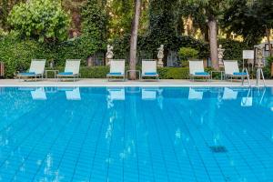 a swimming pool with chaise lounges and chairs at Rodos Park in Rhodes Town