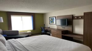 Reidsville的住宿－里茲維爾智選假日套房酒店，酒店客房配有一张床、一张书桌和一台电视。