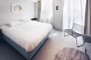 a white bedroom with a bed and a chair at Hotel 171 in Rotterdam