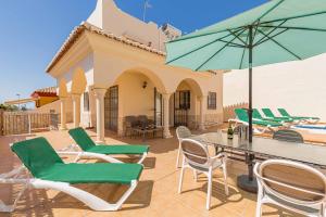 patio z krzesłami, stołem i parasolem w obiekcie Villa Oliva Nerja - Luxury Redesign & Private Pool w mieście Nerja
