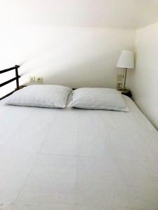 1 dormitorio con 1 cama blanca y 2 almohadas en Coeur de Bastide, en Burdeos