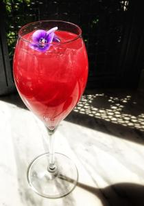 a red drink in a glass with a purple flower in it at A for Athens in Athens