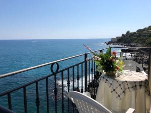 a table with flowers on a balcony with the ocean at La Casa Sulla Scogliera in Cefalù