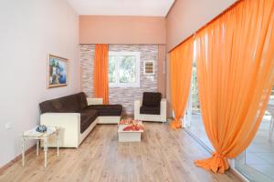 - un salon avec des rideaux orange et un canapé dans l'établissement Dreamy Villa, à Skala Kallirakhis