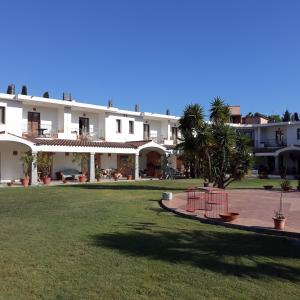 un gran edificio blanco con un césped verde delante de él en Hotel Domu Incantada, en Muravera