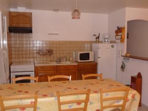 a kitchen with a table and a white refrigerator at le marais in LʼÉguille