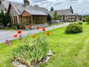 a house with a garden with red flowers in the yard at Shetland Cottage Kincraig in Kincraig