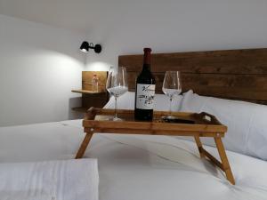 a bottle of wine and two glasses on a tray on a bed at Hostal Cuéntame Evolución Auto Check in in Burgos