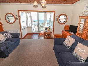 uma sala de estar com sofás azuis e vista para o oceano em Min Y Traeth em Amlwch