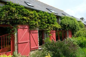 um celeiro vermelho com plantas ao lado dele em La Maison Jaune à la Janaie em Parigné