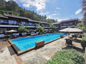 ein Pool in einem Resort mit Tischen und Sonnenschirmen in der Unterkunft The Barat Tioman Beach Resort in Kampong Juara