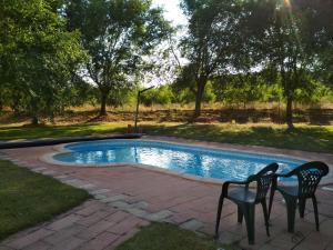 uma piscina com duas cadeiras num quintal em Casa Rural La Galana Albacete em Chinchilla de Monte Aragón