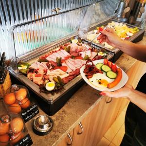 a person holding a plate of food on a buffet at Hotel RICHTR in Frýdek-Místek