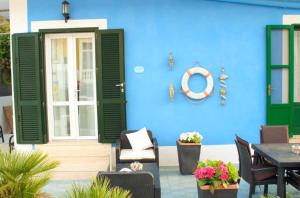 uma casa azul com persianas verdes, uma mesa e cadeiras em Rosa Dei Venti Ponza em Ponza
