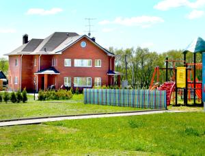une maison rouge avec une aire de jeux dans une cour dans l'établissement Baza otdykha Ozero PONTI, à Gzhel'