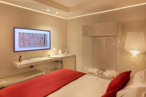 - une chambre avec un lit et une télévision murale dans l'établissement Palazzo Marletta Luxury House Hotel, à Catane