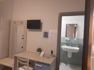 a bathroom with a sink and a table and a mirror at AFFITTACAMERE BORGATA MARINA in Roseto Capo Spulico