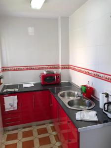 una pequeña cocina con armarios rojos y fregadero en Bonitas habitacións en piso compartido casa antonio, en Sevilla