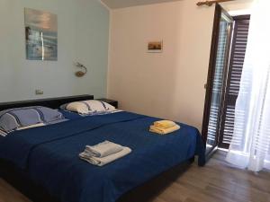 a bedroom with a blue bed with towels on it at Draga Rooms in Njivice