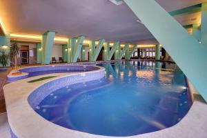a large swimming pool in a hotel lobby at Hotel Ciucas in Băile Tuşnad