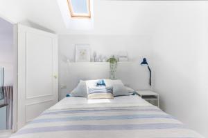 a white bedroom with a bed with blue and white pillows at Duplex Terraza Rivera Marisco 2 Dormitorios 2 Baños in El Puerto de Santa María +13 photos