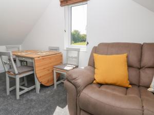 a couch with a yellow pillow sitting next to a desk at Little Valley View in Hayle