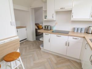 a kitchen with white cabinets and a wooden floor at Little Valley View in Hayle