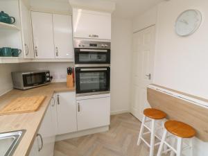 a kitchen with white cabinets and a counter with stools at Little Valley View in Hayle