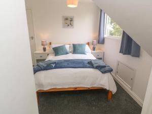 a bedroom with a bed with blue pillows and a window at Little Valley View in Hayle