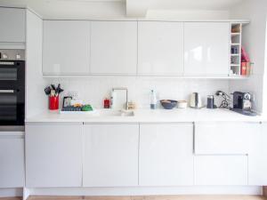 a white kitchen with white cabinets and a sink at Modern & Peaceful Family Home with Private Garden in London