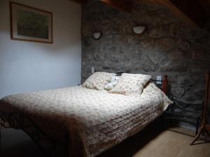 a bedroom with a bed and a stone wall at LE MYRO in Péreyres
