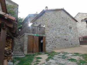 an old stone building with a wooden gate and a door at LE MYRO in Péreyres +3 photos