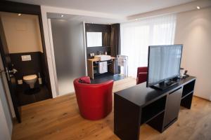 een woonkamer met een rode stoel en een bureau bij Elite Alpine Lodge - Apart & Breakfast in Saas-Fee