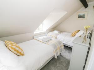 - 2 lits dans une chambre mansardée avec des murs blancs dans l'établissement Victoria Cottage, à Chipping Norton