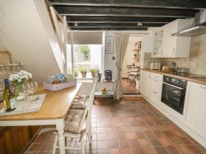 a kitchen with a table and chairs and a counter at Thimble Cottage in Cheltenham